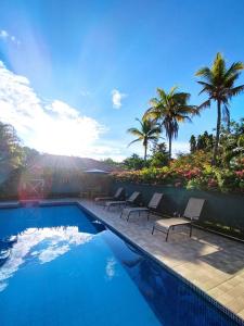 a swimming pool with lounge chairs and palm trees at Las Catalinas Coronado in Playa Coronado