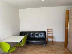 un sofá de cuero negro en una habitación con mesa y sillas en Cavendish house en Strawberry Hill