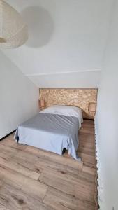 een bed in een witte kamer met een houten vloer bij Studio du lac in Serres-Castet