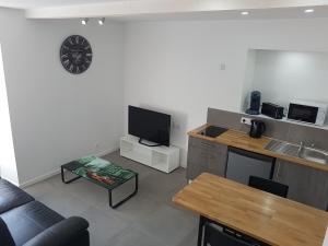 ein Wohnzimmer mit einem Sofa, einem TV und einem Tisch in der Unterkunft Appartement entre Saint-Malo, Dinard, Dinan et Dol in Miniac-Morvan
