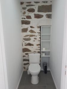 La salle de bains est pourvue de toilettes et d'un mur en pierre. dans l'établissement Appartement entre Saint-Malo, Dinard, Dinan et Dol, à Miniac-Morvan