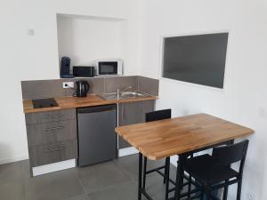eine Küche mit einem Holztisch und einem Waschbecken in der Unterkunft Appartement entre Saint-Malo, Dinard, Dinan et Dol in Miniac-Morvan