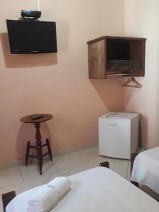 a room with a bed and a table and a tv at Pousada Licuri in Serra do Cipo