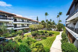 an apartment courtyard with a garden and palm trees at Casa De Emdeko 230 in Kailua-Kona