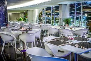 a restaurant with white tables and white chairs at Lidotel Paraguaná in Punto Fijo