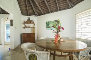 Island Breeze Beach Villa في Carey Park: غرفة طعام مع طاولة وكراسي خشبية