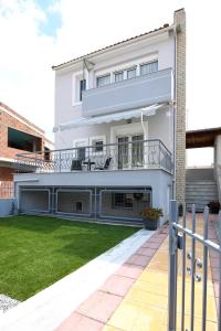 ein weißes Haus mit einem Balkon und einem Hof in der Unterkunft Villa Bolero in Nea Iraklitsa