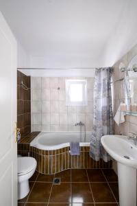 a bathroom with a tub and a toilet and a sink at Villa Bolero in Iraklitsa