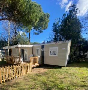 uma pequena casa num quintal com uma cerca de madeira em Superbe Mobil home 6-8 personnes (57) em Saint-Jean-de-Monts