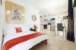 a white bedroom with a large bed and a kitchen at Di Valentina Boutique Living in Sliema