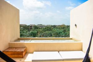 a room with a balcony with a view of trees at Eterna Tulum in Tulum