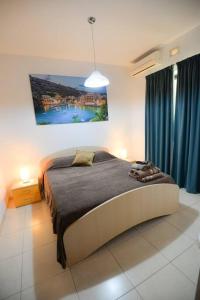 a bedroom with a large bed with blue curtains at Seaside Xlendi apartment in Xlendi