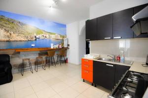 a kitchen with a painting of a river on the wall at Seaside Xlendi apartment in Xlendi