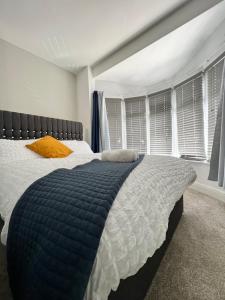 a bedroom with a bed with a blue comforter and windows at Cosy Family Get-Away 4 Bedrooms 7 Beds 2 Bathrooms in Blackpool