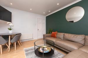 sala de estar con sofá, mesa y espejo en The Edinburgh Meadows Apartment, en Edimburgo