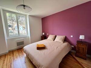 een slaapkamer met een groot bed met een paarse muur bij Refuge de luxe pour les amoureux de la montagne in Pouzac