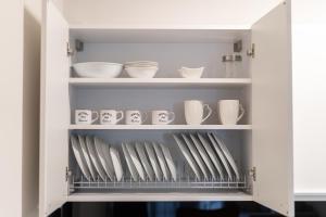 a cupboard filled with white dishes and bowls at Lux Palace Trikala in Tríkala
