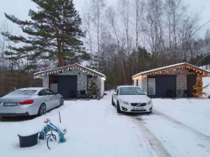 two cars parked outside a house in the snow at Domki letniskowe Leśny Chillout in Solina