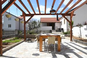 a patio with a wooden pergola and a table and chairs at Villa Ella Tvrdos in Trebinje