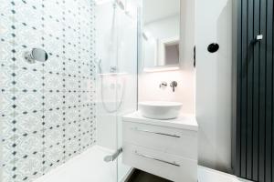 a white bathroom with a shower and a sink at Apartament Piotrkowska 97 in Łódź