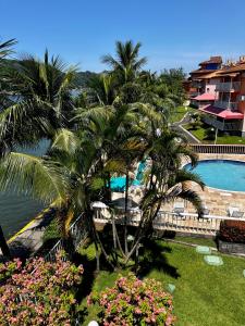 a view of a resort with palm trees and a swimming pool at Apartamento em Itacuruça em frente ao mar. in Itacuruçá