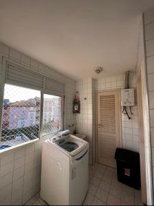 a washing machine in a bathroom with a window at Apartamento em Itacuruça em frente ao mar. in Itacuruçá