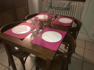 una mesa de madera con servilletas rosas y platos en ella en le vieux relais en Cosne-Cours-sur-Loire