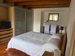 1 dormitorio con 1 cama blanca grande y TV en La Luna nei Sassi en Matera