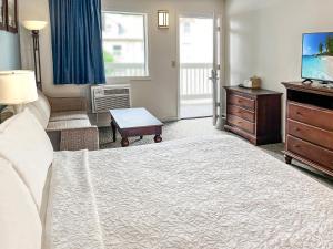 um quarto com uma cama, uma cómoda e uma televisão em Chincoteague Inn em Chincoteague