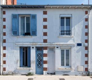 een wit huis met blauwe ramen en een blauwe deur bij La Mariennée in La Rochelle
