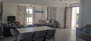 uma sala de estar com sofás, uma mesa e cadeiras em Kiti Village Villa Larnaca, salt-water pool, 5 bedrooms em Kiti
