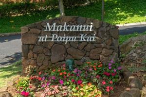 a sign for a park with flowers in a garden at Kauai Makanui by Coldwell Banker Island Vacations in Koloa