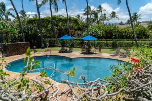 una piscina con sillas y sombrillas azules en Kauai Makanui by Coldwell Banker Island Vacations, en Koloa