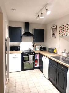 a kitchen with black cabinets and white appliances at Wee Silverburn in Whiting Bay