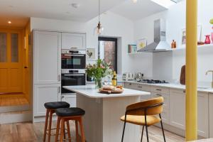 a kitchen with white cabinets and bar stools at House on Beaconsfield spacious seaside home perfect for relaxing with friends or family in Deal