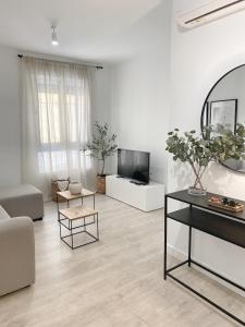a white living room with a couch and a tv at Smart Stay Córdoba in Córdoba