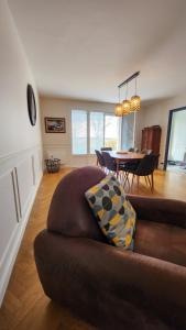 een woonkamer met een bruine bank en een tafel bij Le gîte du peintre in Entrains-sur-Nohain +4 foto's