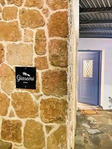 a stone wall with a blue door and a sign on it at Giasemi Aegina, Modern House in Áyioi Asómatoi