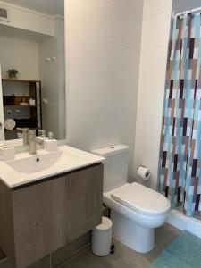 a bathroom with a sink and a toilet and a mirror at Apart Center Temuco in Temuco