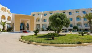 Telemaque Beach & Spa - All Inclusive - Families and Couples Only في حومة السوق: عمارة سكنية كبيرة امامها شجرة