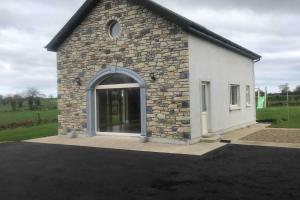 a stone building with a large window in a parking lot at Ard Alainn Lodge, Adorable Setting, scenic views in Grange