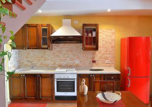 cocina con armarios de madera y nevera roja en Casa Vacanze La Graziella - LA DÉPENDANCE, en Ferrandina