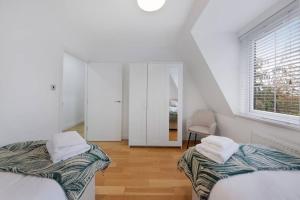 Habitación blanca con 2 camas y ventana en Roomy One bed loft apartment en Bishops Stortford
