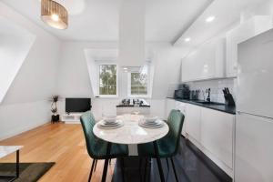 ビショップス・ストートフォードにあるRoomy One bed loft apartmentの白いキッチン(テーブル、緑の椅子付)