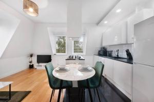a white kitchen with a table and green chairs at Roomy One bed loft apartment in Bishops Stortford