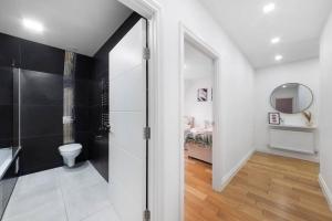 a bathroom with a shower and a toilet and a bedroom at Roomy One bed loft apartment in Bishops Stortford