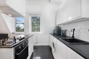 a white kitchen with a stove and a sink at Roomy One bed loft apartment in Bishops Stortford