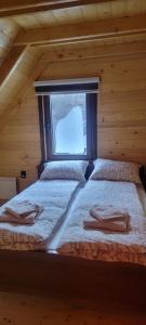 two beds in a log cabin with a window at Apartmani Prica in Crni Vrh
