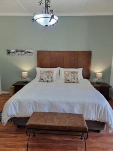 a bedroom with a large bed with a wooden headboard at Sonskyn Hof Guest House / Gastehuis in Jan Kempdorp