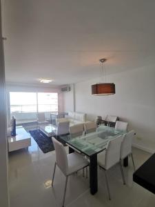 Un comedor con una mesa de cristal y sillas blancas. en ITALIFOREST1203, en Punta del Este